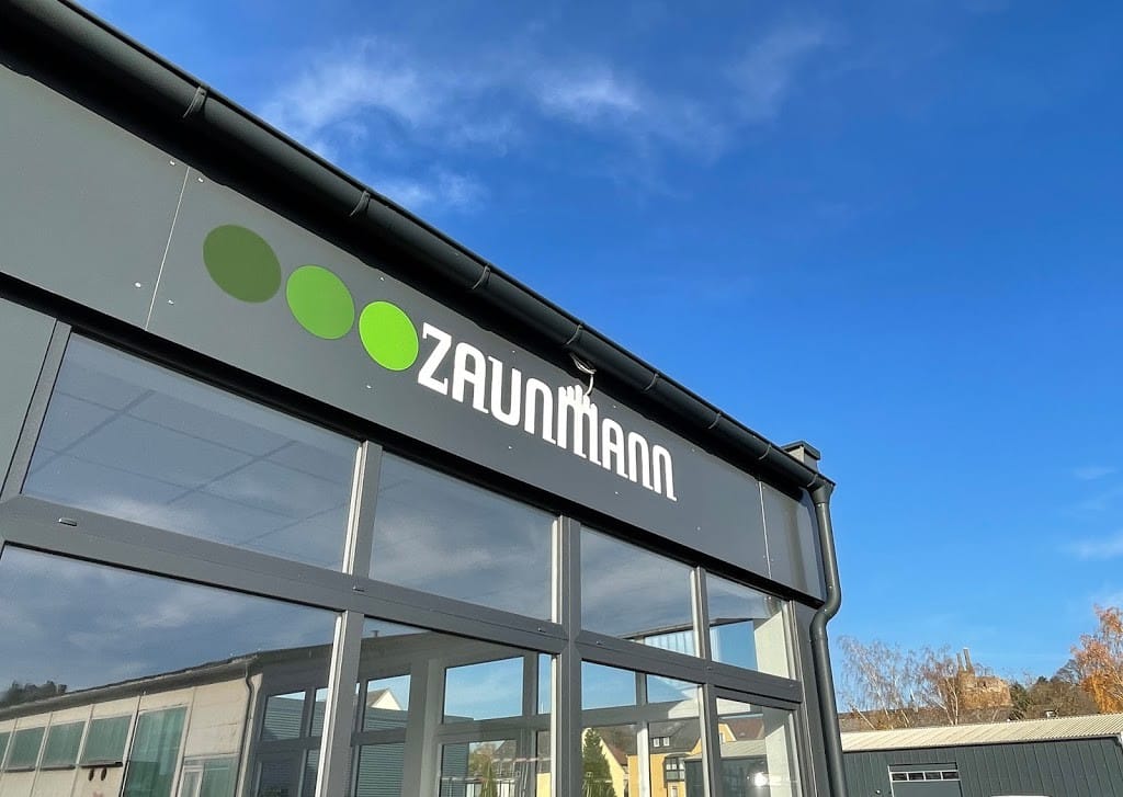 Betriebsgebäude von Zaunmann in Wetzlar: Glasfassade mit ZAUNMANN-Schriftzug vor blauem Himmel