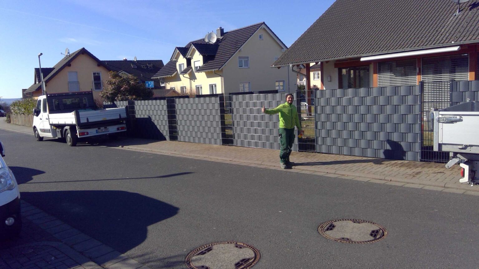 Monteur vor fertigem Doppelstabzaun mit Sichtschutzstreifen – Projektfoto 10