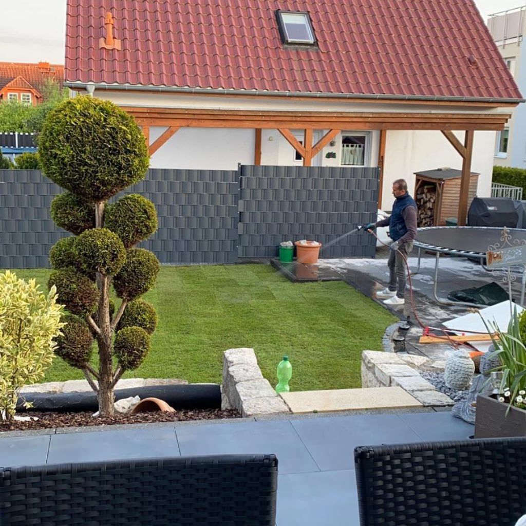 Sichtschutzzaun im Garten, Mann wässert frisch verlegten Rasen – Projektfoto 1